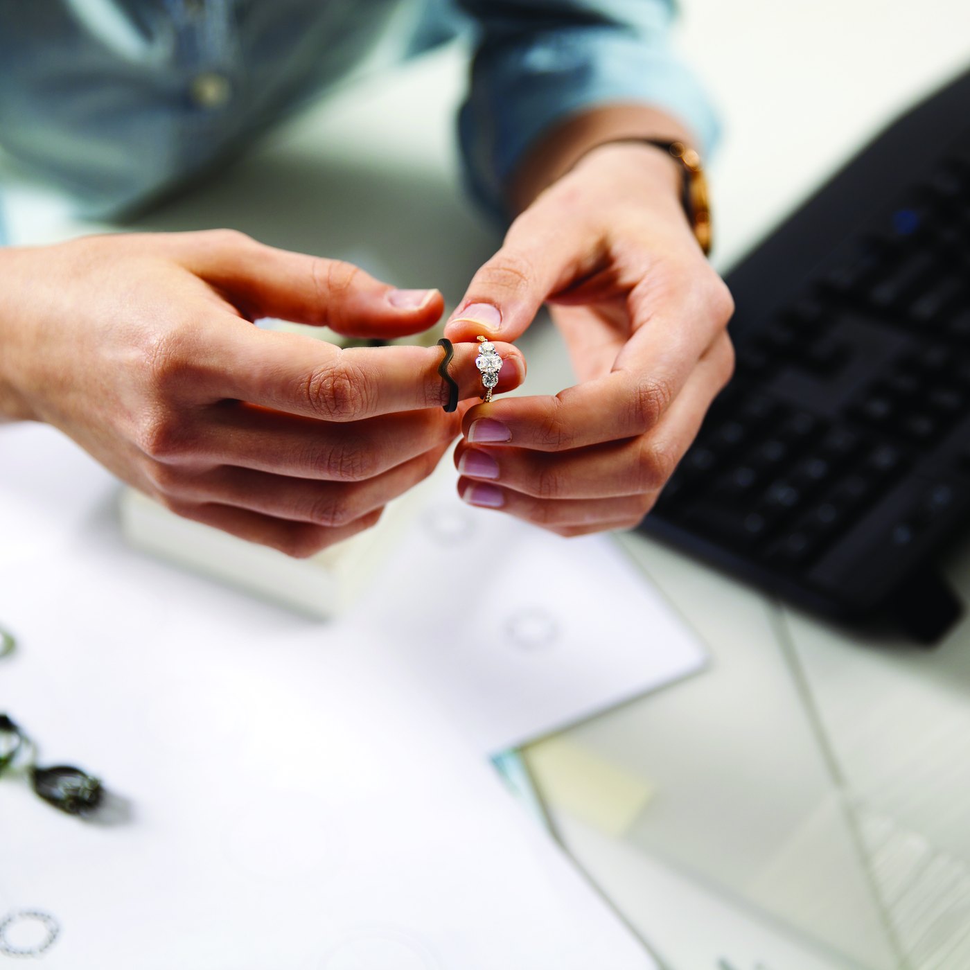 A jeweller checking a ring design against the original drawings