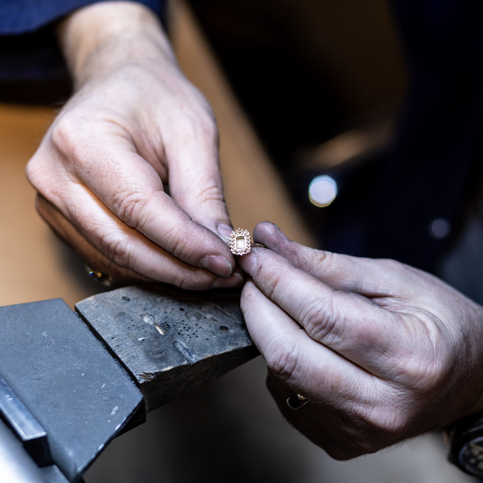 A jeweller setting a stone into a ring at the workshop bench
